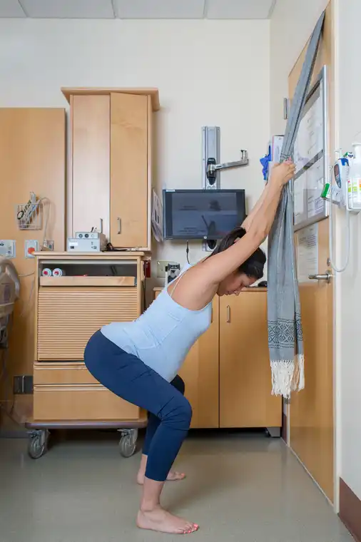 Grávida em posição pendurada com apoio num xale preso à porta