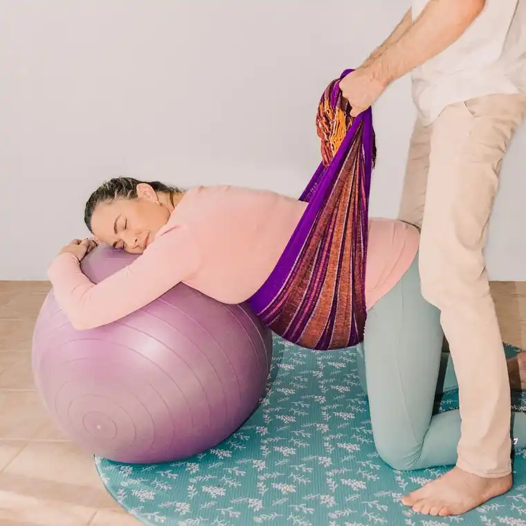 Grávida apoiada numa bola enquanto recebe Rebozo Manteada